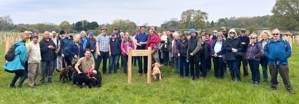 A large group of people gathered around the Forster Wood sign